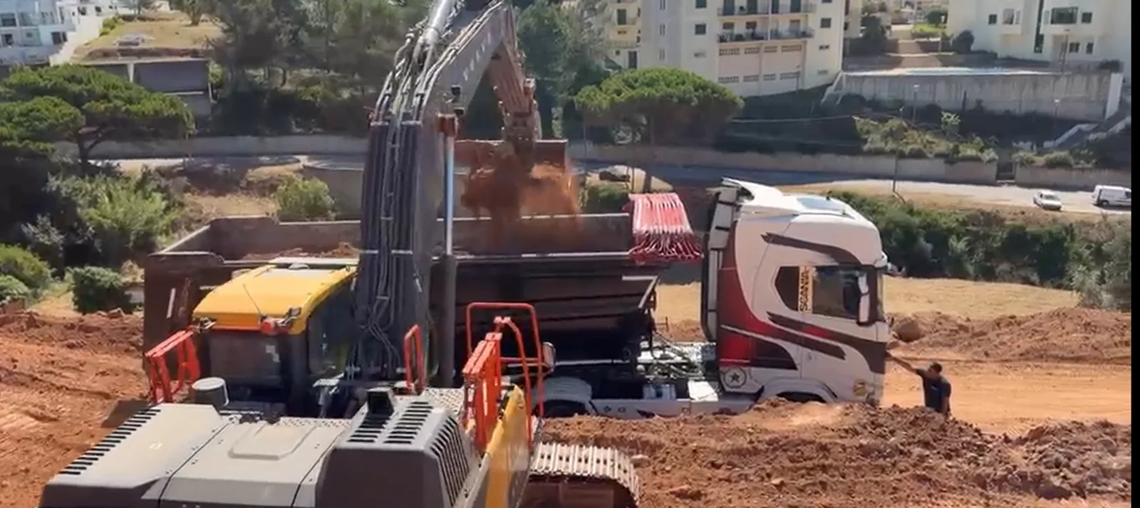 Escavadora a carregar camião para apoio ao transporte de terras